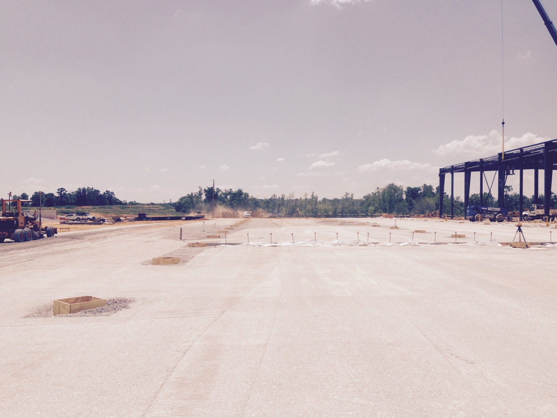A large empty construction site with a crane in the background