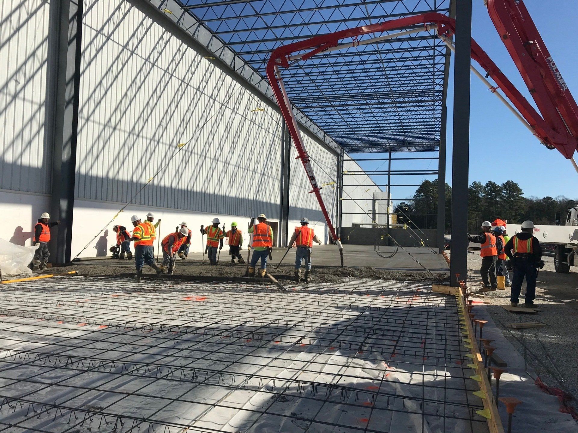 A group of construction workers are working on the floor of a building.