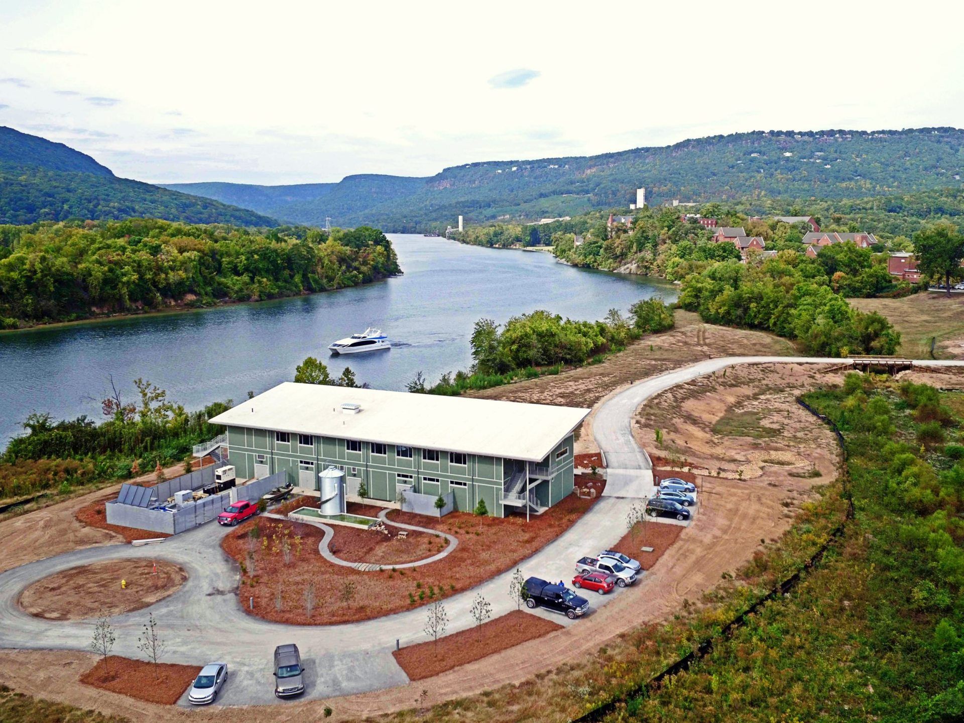 An aerial view of a house next to a river with a boat in the water.