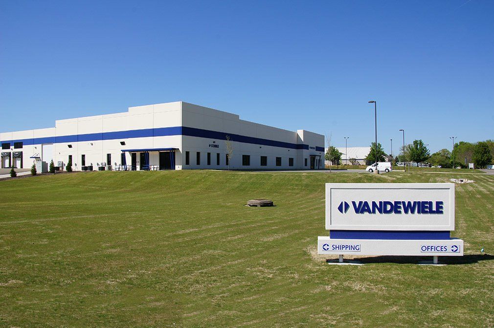 A large white building with a sign that says vandewiele in front of it