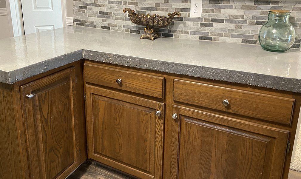 A kitchen with wooden cabinets and a concrete counter top.