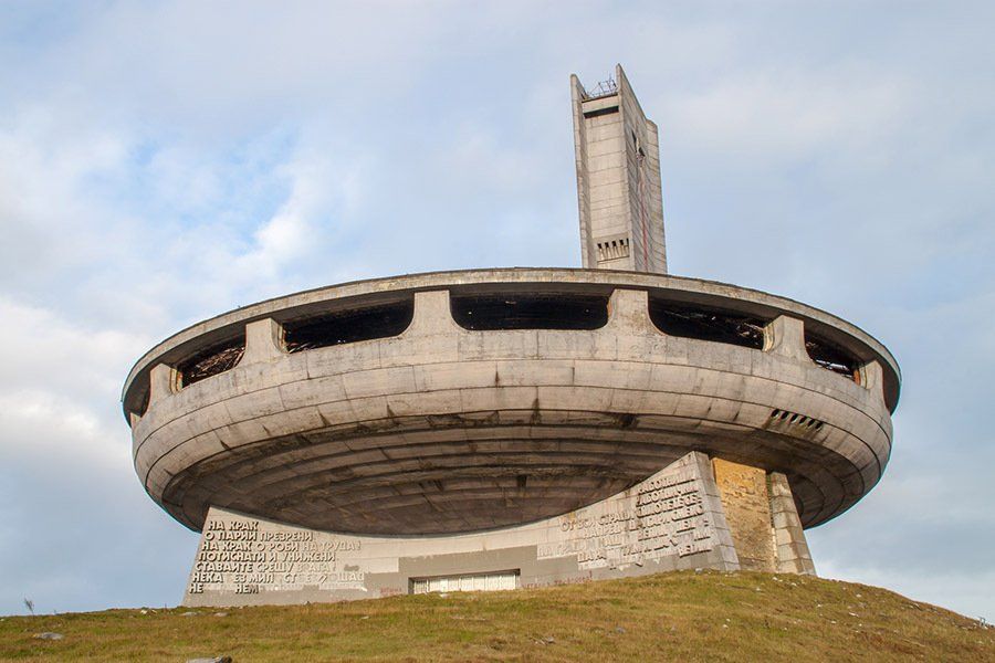 A large concrete building is sitting on top of a grassy hill.