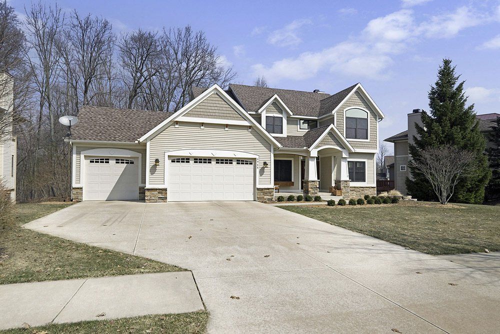 A large house with a concrete driveway and a satellite dish on the roof