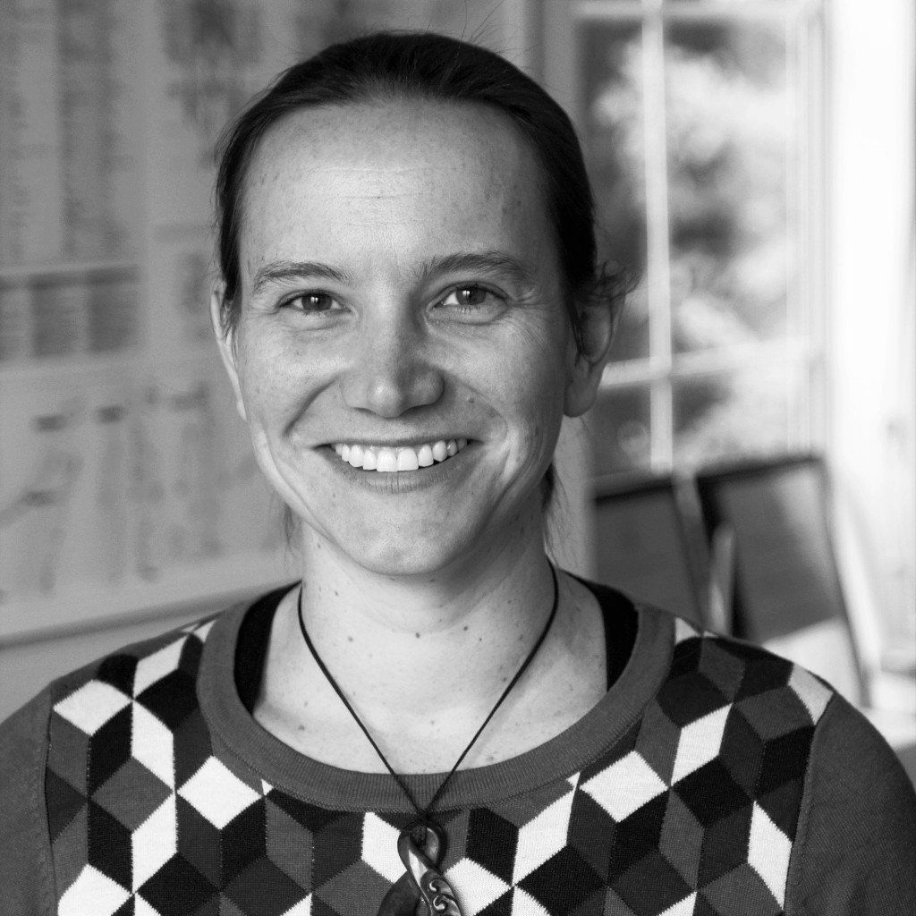 A black and white photo of a woman wearing a sweater and smiling.