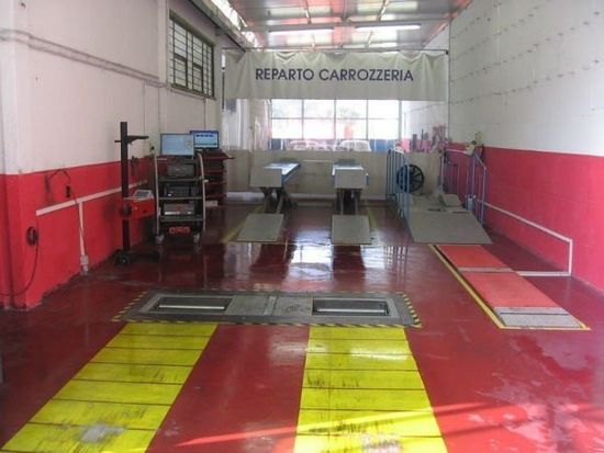 officina vista dall' esterno con tettoia e macchine parcheggiate