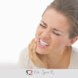 Mulher com a mão na bochecha, fazendo careta devido à dor de dente.
