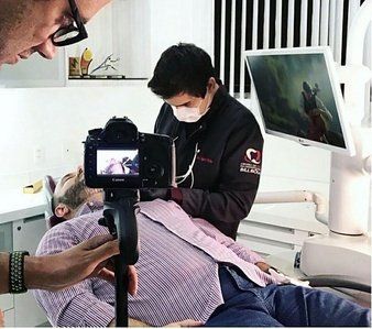 Un dentista scatta foto della bocca di un paziente con una macchina fotografica montata su un treppiede in uno studio dentistico.
