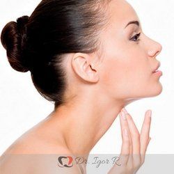 Mulher tocando o pescoço, examinando a pele. Ela está com o cabelo preso em um coque, vista de perfil.