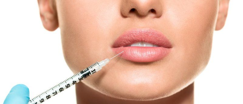 Inyección en los labios de una persona con una jeringa. Primer plano, fondo blanco.