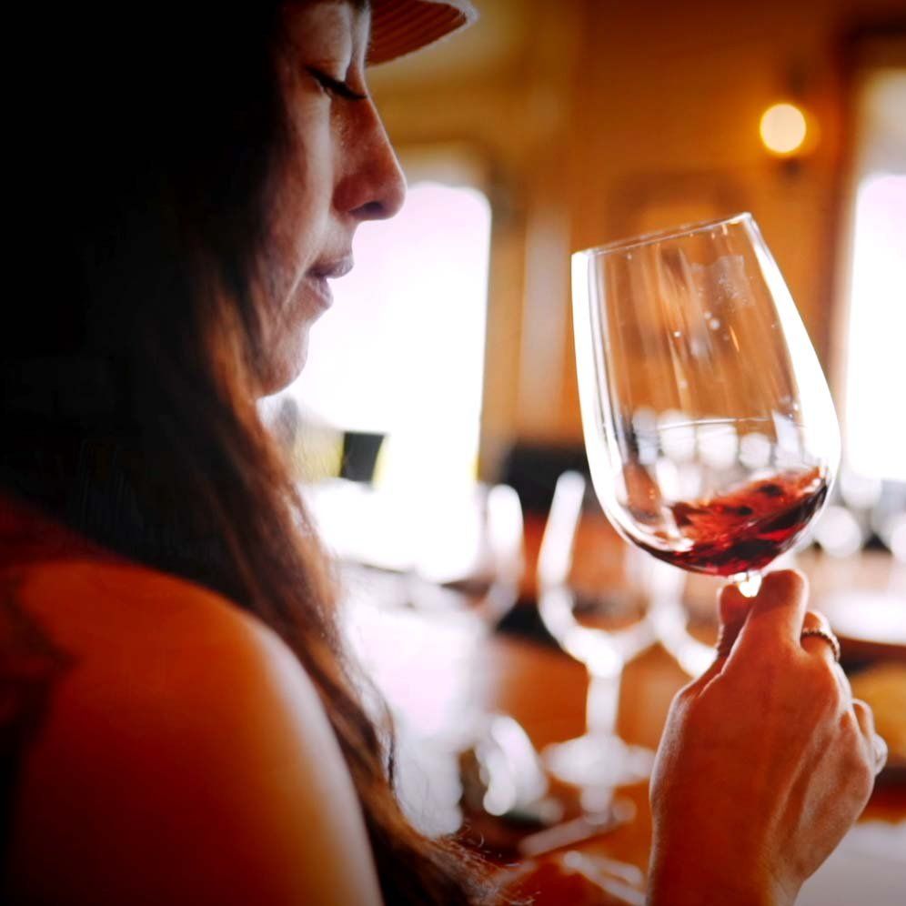A woman is drinking a glass of red wine