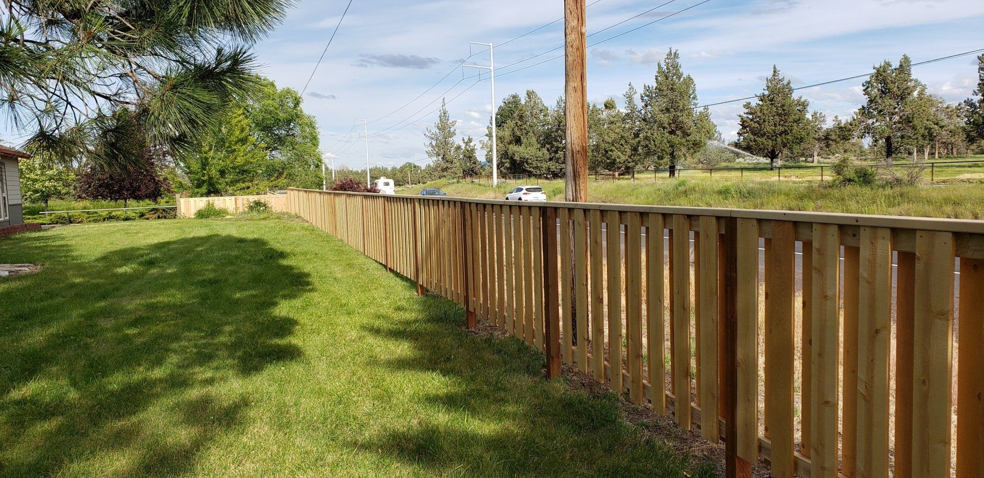 Long wooden fence installed along grassy property line