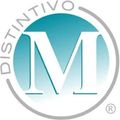 Logotipo de Distintivo con una gran M blanca en un círculo verde azulado, rodeado por un anillo gris y texto.