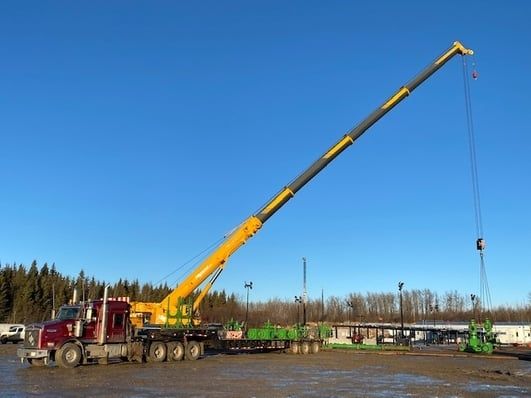 A picture of a crane company doing work on a wellhead with a yellow crane.