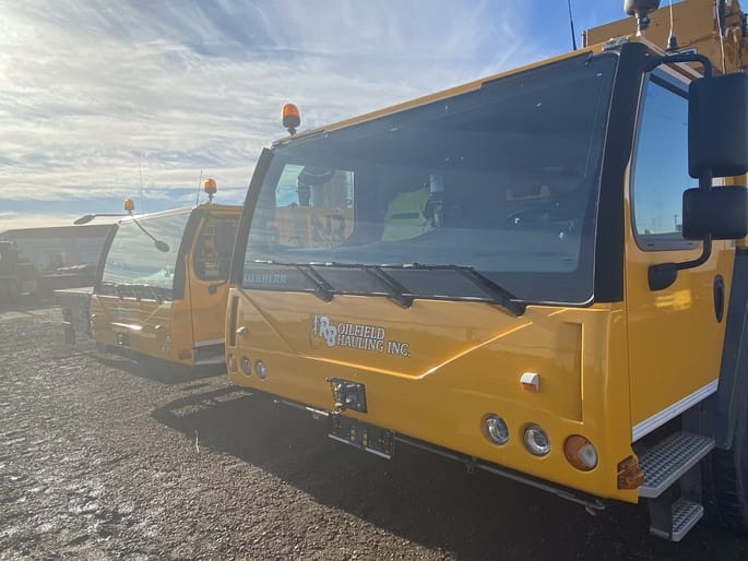 A picture of two yellow crane rentals parked in a yard.