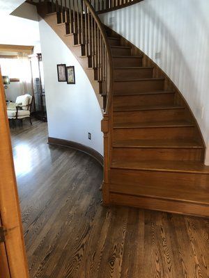 Curved wooden staircase in a home with hardwood floors and white walls