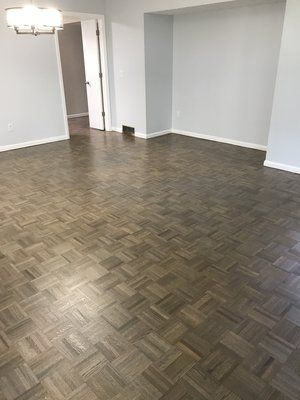 Empty room with dark herringbone wood floor and white walls, seen from the doorway.