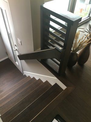 Staircase with dark wood steps and a black safety gate beside a white wall.