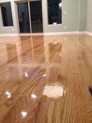 Shiny hardwood floor with wet patches in a sparsely furnished room with sliding glass doors