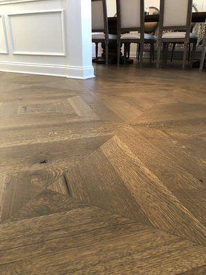 Wood-patterned herringbone floor in a dining room, with chairs and a table in the background.