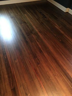 Empty room with glossy dark wood flooring and sunlight reflection near the wall.