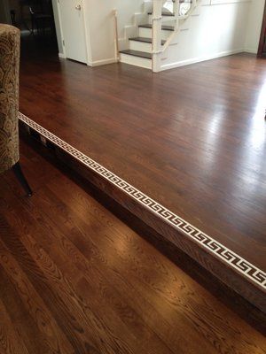 Interior with dark wood flooring and a raised threshold strip, viewed near a staircase.