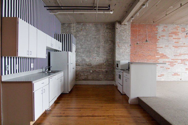 Modern kitchen with white cabinets, brick wall, wood floor, and a built-in bench area