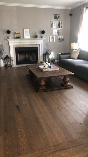 Living room with a fireplace, dark wood floors, gray sofa, and coffee table in the center.