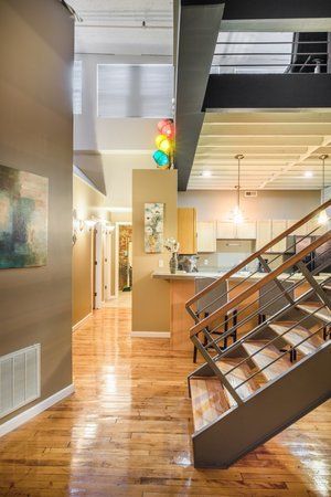 Modern loft interior with hardwood floors, staircase, kitchen, and high ceilings