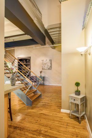 Modern loft interior with metal staircase, wooden floor, and small side table against a white wall