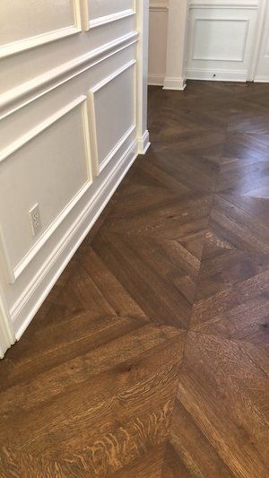 Wooden herringbone floor in a white-paneled hallway near a doorway