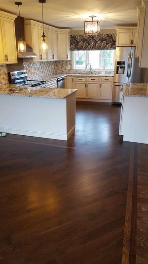 Modern kitchen with dark wood floors, white cabinets, pendant lights, and a window over the sink