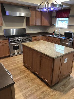 Kitchen with stainless steel appliances, wood cabinets, and a central granite island.
