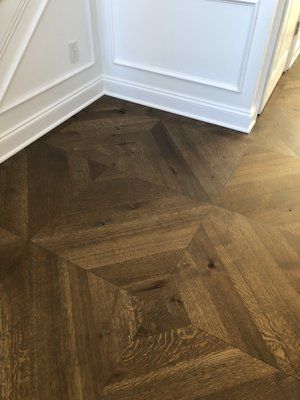 Dark herringbone wood floor in a white hallway corner with baseboards and wall molding.