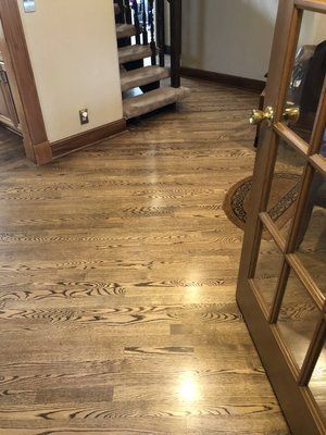 Hallway with polished hardwood floor, staircase ahead, and glass-paneled door on the right