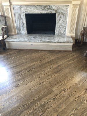 Marble fireplace with dark opening in a room with light wood flooring and cream trim