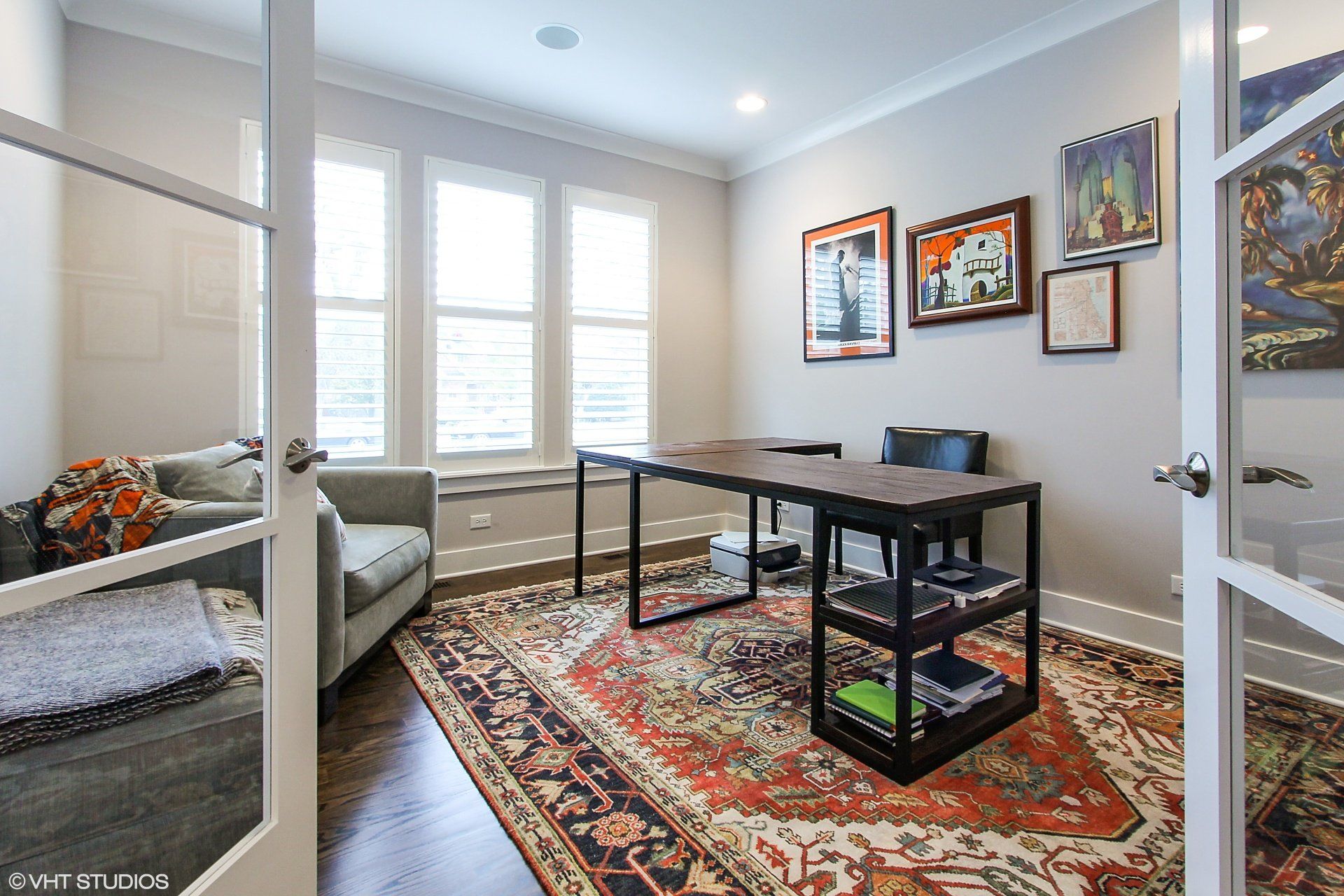 A living room with a rug , a desk , and a couch.