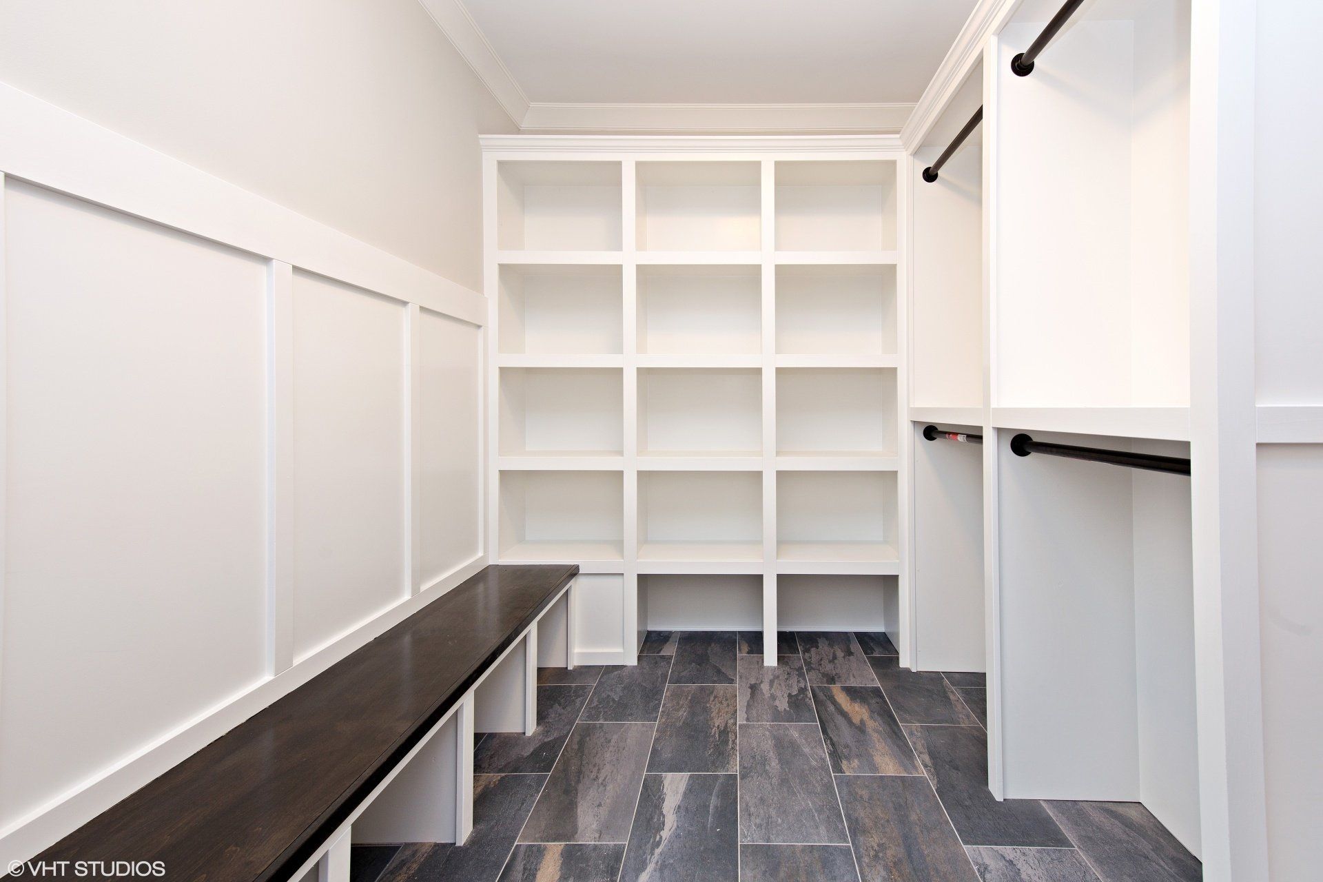 A walk in closet with lots of shelves and a bench