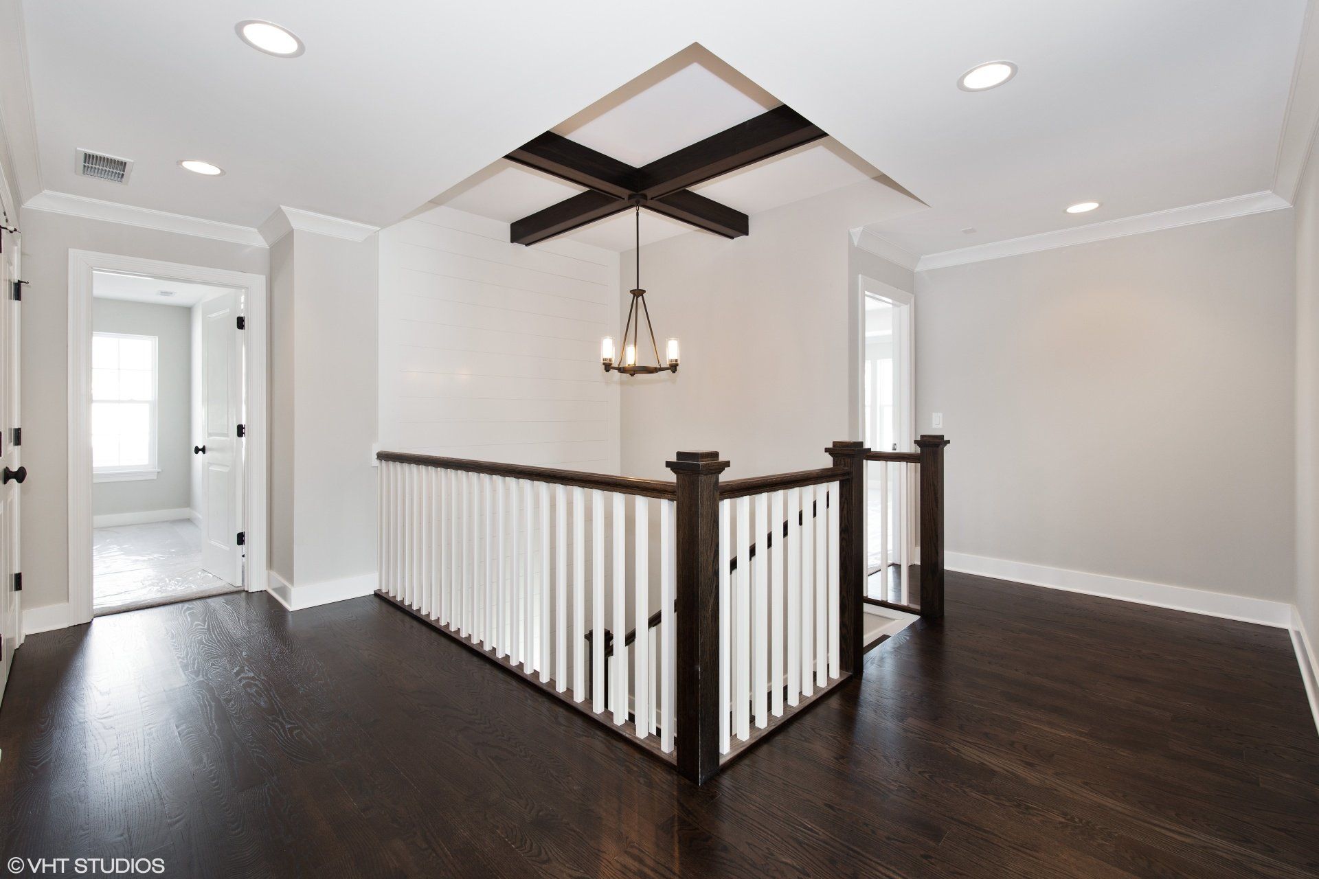 An empty room with a staircase and a chandelier hanging from the ceiling.