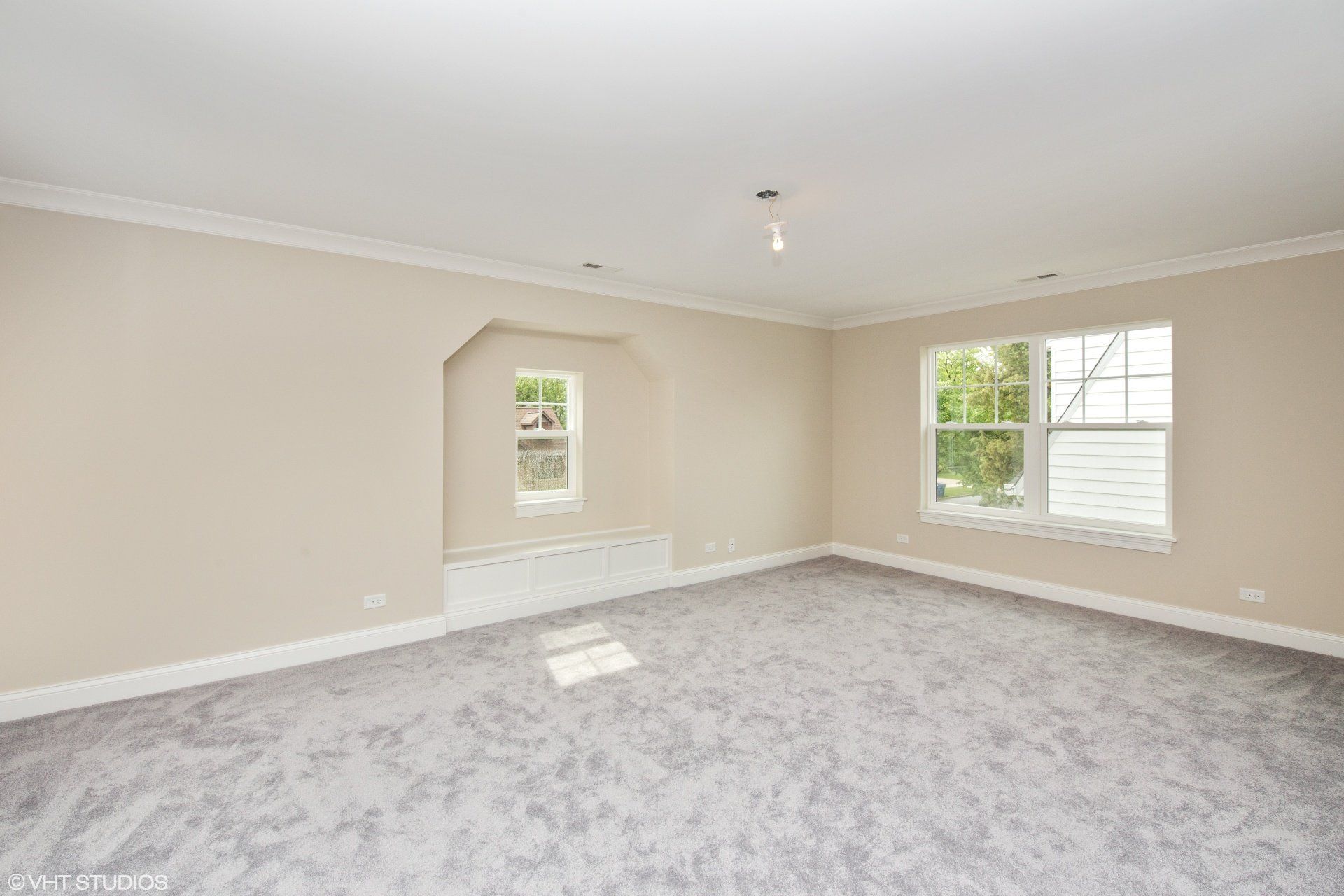 An empty room with a carpeted floor and two windows.