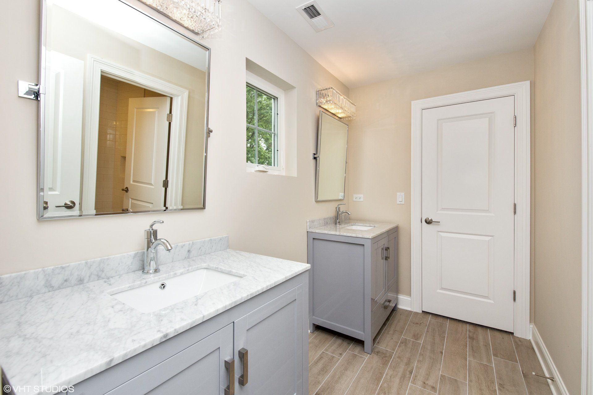 A bathroom with a sink , mirror and window.