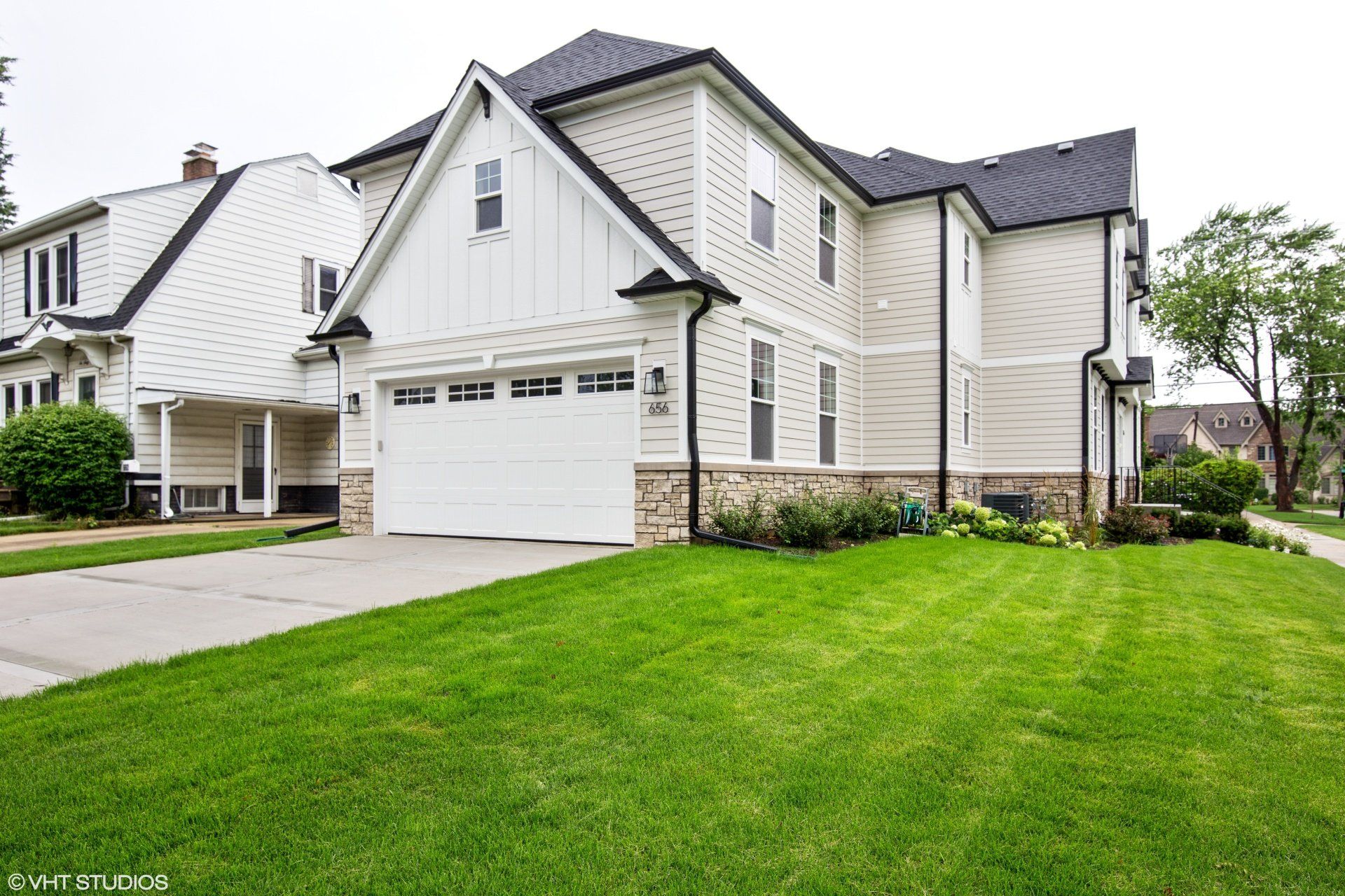 A large white house with a black roof and a white garage door