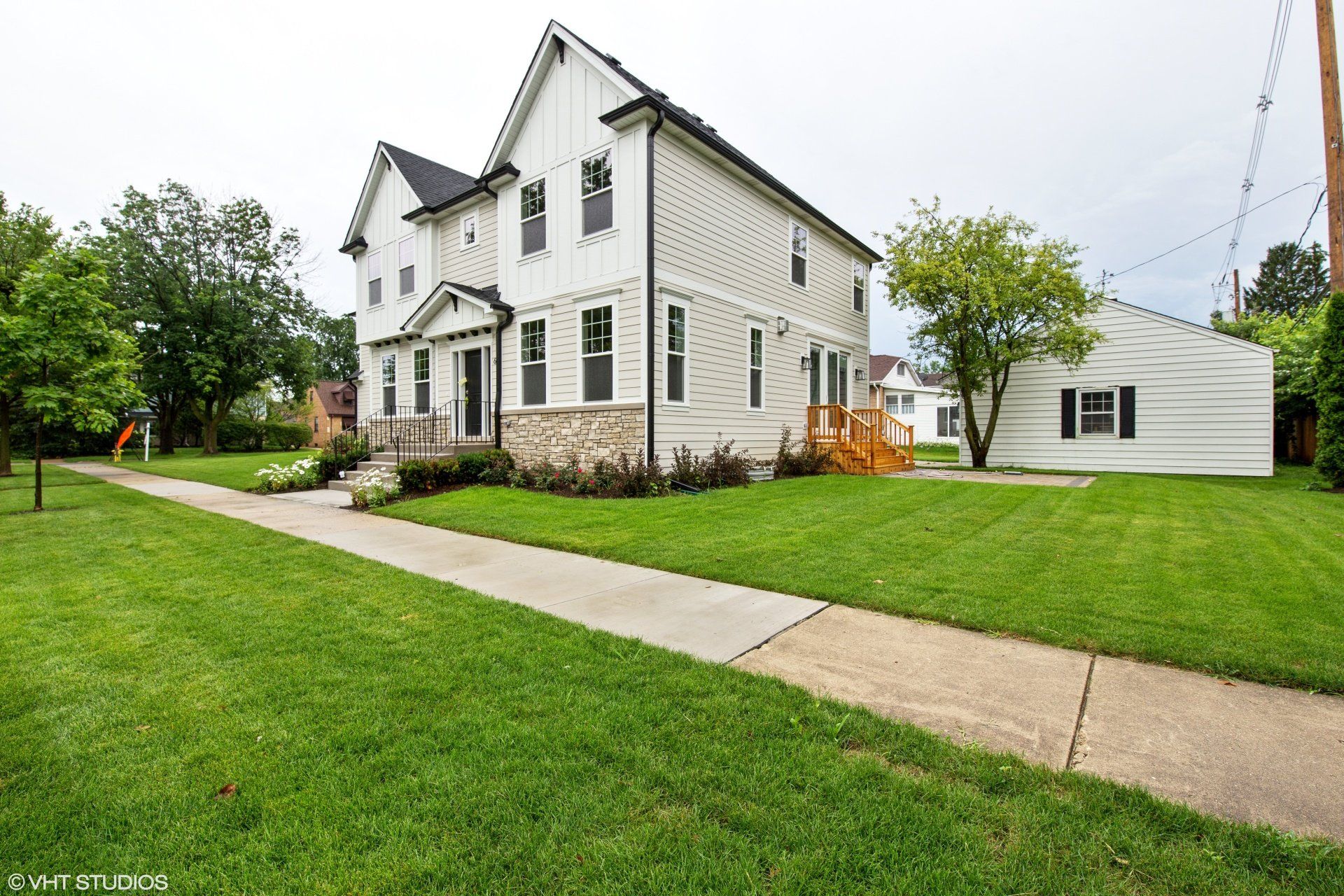 A large white house with a lush green lawn and a sidewalk in front of it.