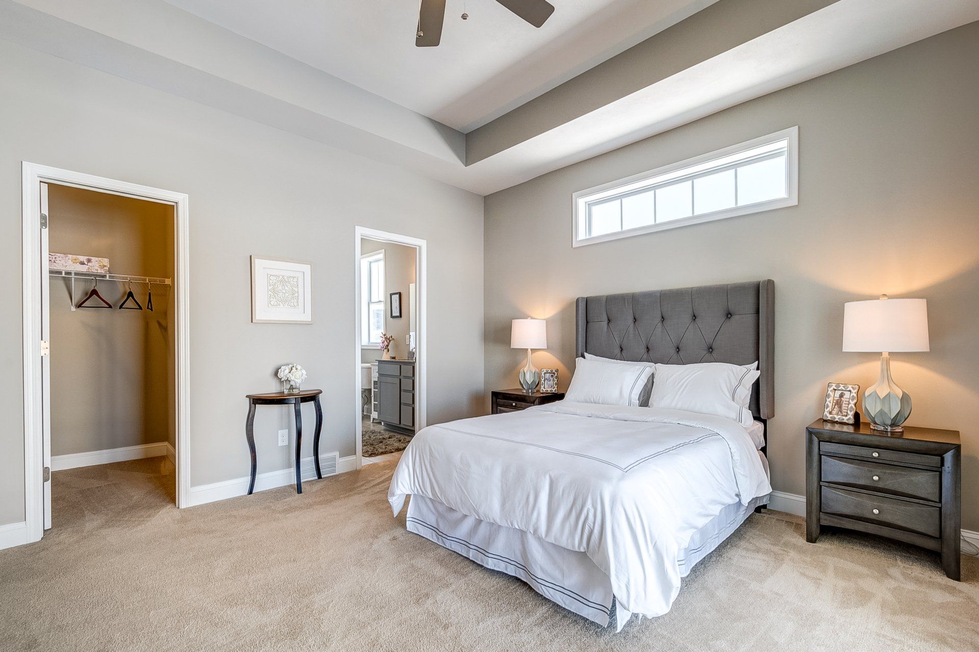 primary bedroom with recessed ceiling and ceiling fan