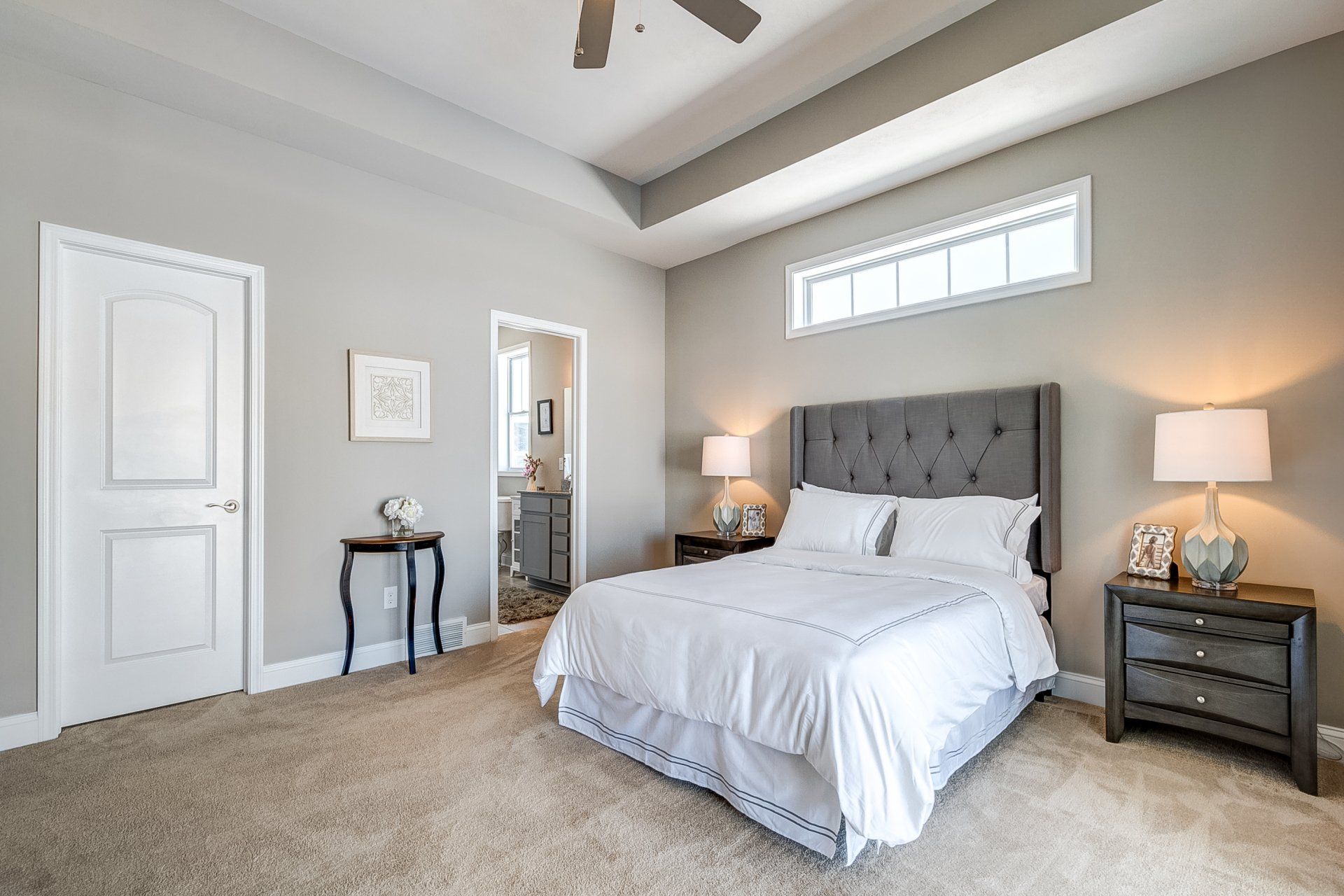 primary bedroom with recessed ceiling and ceiling fan