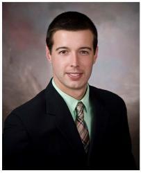 Portrait of a man in a dark suit and patterned tie against a studio backdrop