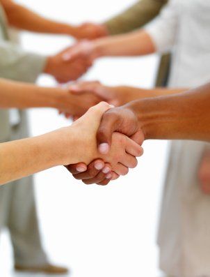 Hands of several people shaking in a circle, symbolizing teamwork and agreement