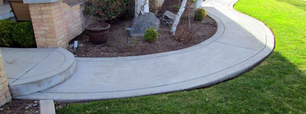 A curved concrete walkway leading to a house with steps.
