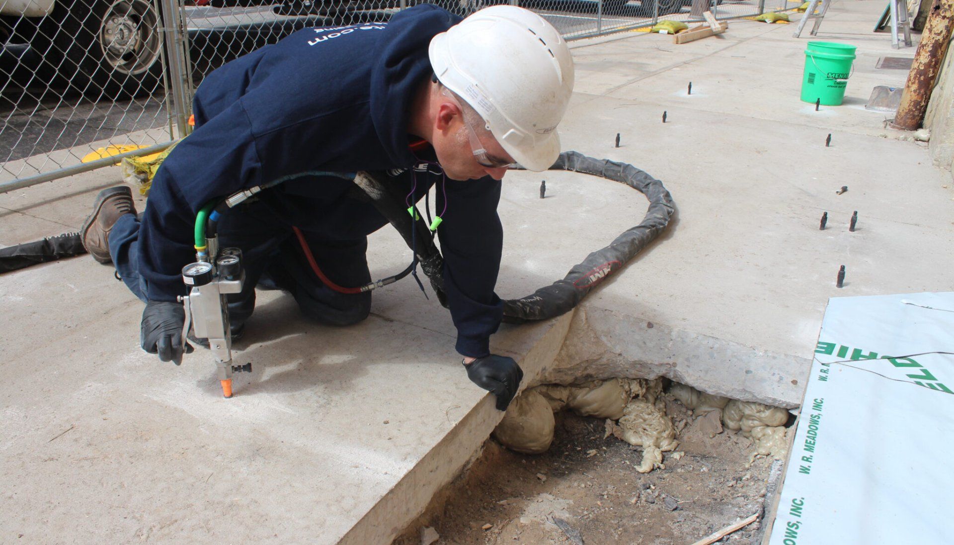 A man wearing a hard hat is working on a concrete surface