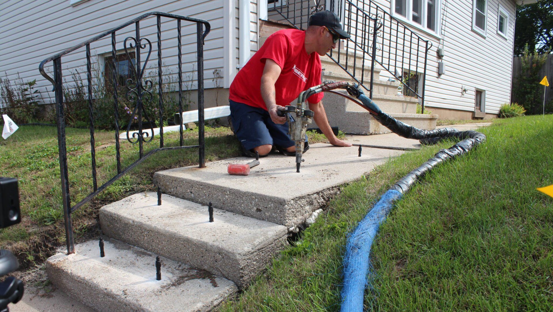 A man is kneeling down next to a set of stairs in front of a house.