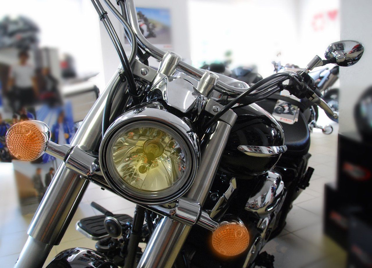 Eine Nahaufnahme zeigt ein Cruiser-Motorrad mit großem Scheinwerfer, verchromter Gabel und bernsteinfarbenen Blinkern.